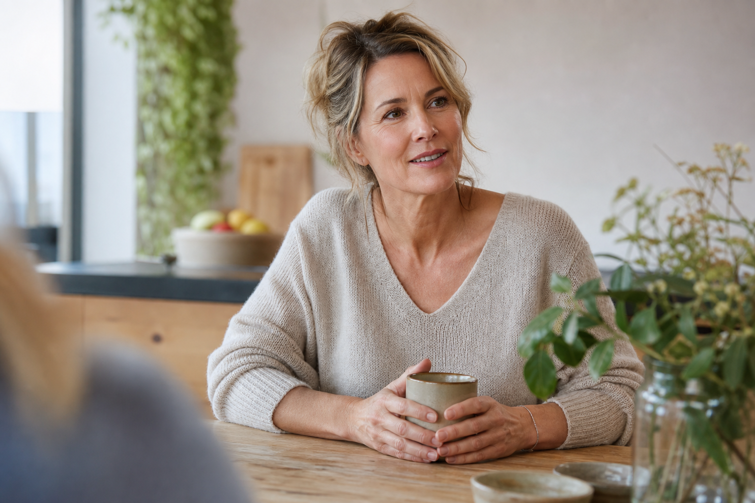Nederlandse vrouw 49+ in gesprek aan keukentafel, warm licht